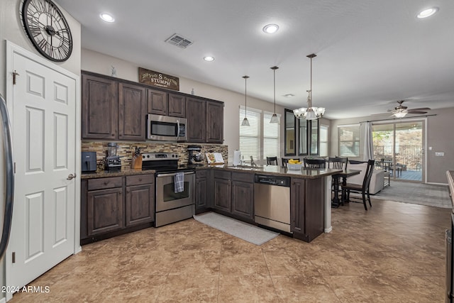 kitchen featuring tasteful backsplash, appliances with stainless steel finishes, dark brown cabinets, kitchen peninsula, and hanging light fixtures