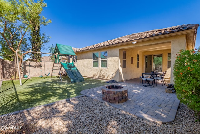 rear view of property with a yard, a patio area, a playground, and a fire pit