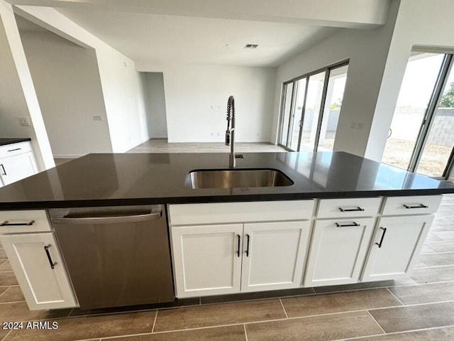 kitchen with a kitchen island with sink, plenty of natural light, stainless steel dishwasher, and white cabinets