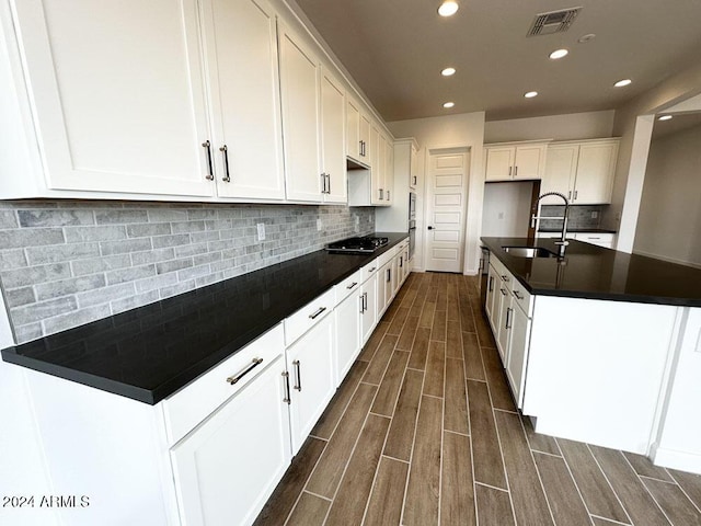 kitchen featuring white cabinetry, sink, black gas stovetop, and decorative backsplash