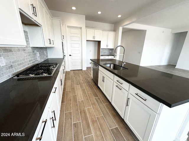 kitchen featuring sink, appliances with stainless steel finishes, a kitchen island with sink, tasteful backsplash, and white cabinets