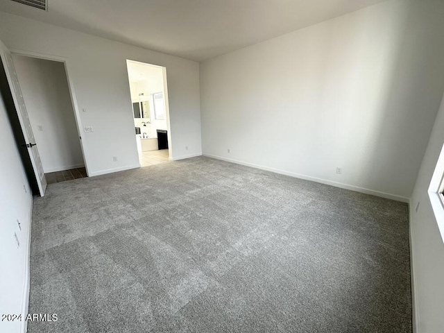 unfurnished bedroom featuring ensuite bathroom and carpet