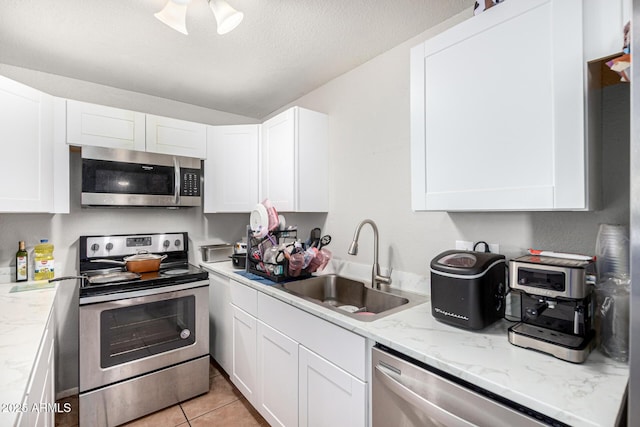 3646 N 67th Ave Unit 29, Phoenix, AZ 85033 - kitchen featuring appliances with stainless steel finishes, white cabinets, light stone counters, a ceiling fan, and light tile patterned floors