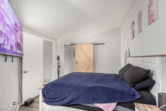 3646 N 67th Ave Unit 29, Phoenix, AZ 85033 - bedroom with a textured ceiling, a barn door, wood finished floors, and lofted ceiling