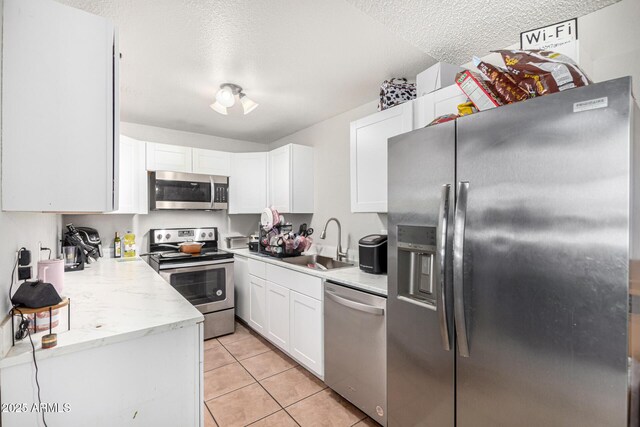 3646 N 67th Ave Unit 29, Phoenix, AZ 85033 - kitchen featuring stainless steel appliances, white cabinets, a textured ceiling, light tile patterned flooring, and light stone counters
