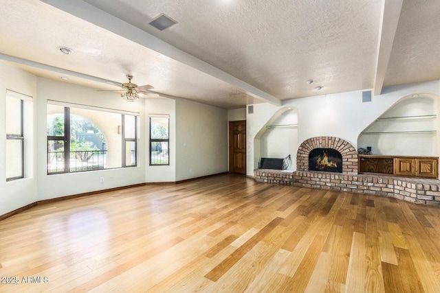 8426 N 15th Dr, Phoenix, AZ 85021 - unfurnished living room with a textured ceiling, wood finished floors, beamed ceiling, baseboards, and a brick fireplace