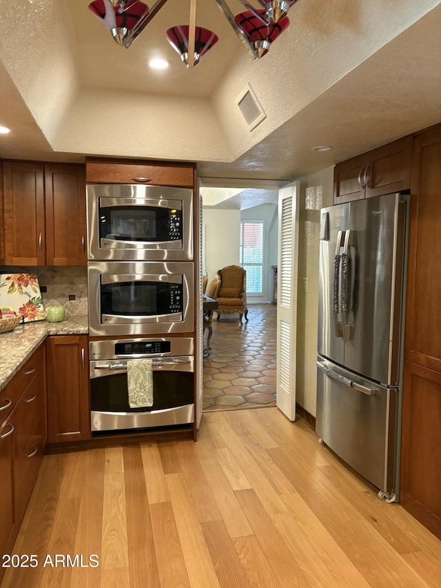 8426 N 15th Dr, Phoenix, AZ 85021 - kitchen with light wood-type flooring, stainless steel appliances, a raised ceiling, light stone countertops, and visible vents