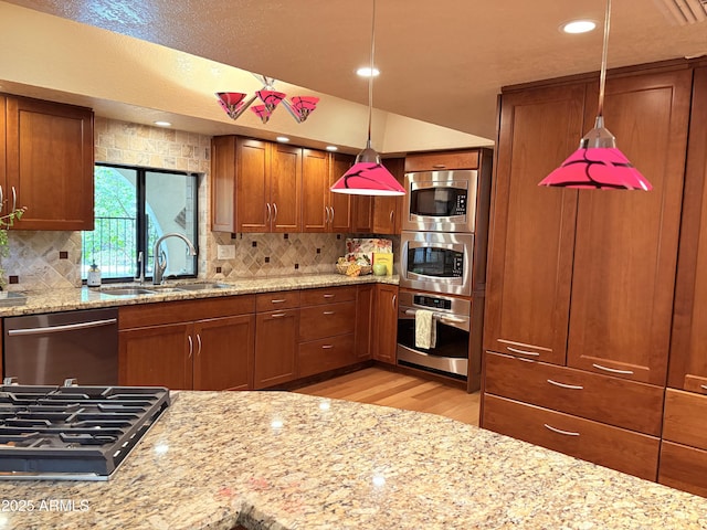 8426 N 15th Dr, Phoenix, AZ 85021 - kitchen featuring a sink, brown cabinetry, pendant lighting, stainless steel appliances, and light wood finished floors