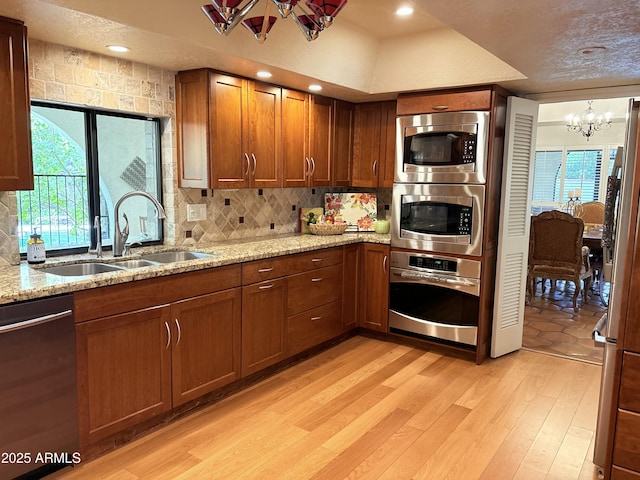 8426 N 15th Dr, Phoenix, AZ 85021 - kitchen with brown cabinets, an inviting chandelier, a sink, light wood-type flooring, and appliances with stainless steel finishes