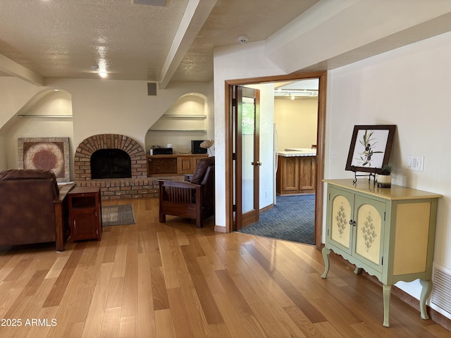 8426 N 15th Dr, Phoenix, AZ 85021 - interior space featuring a fireplace, beam ceiling, a textured ceiling, and light wood-style flooring
