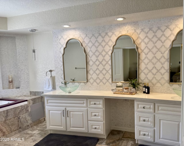 8426 N 15th Dr, Phoenix, AZ 85021 - full bathroom with tiled tub, a sink, a textured ceiling, and double vanity
