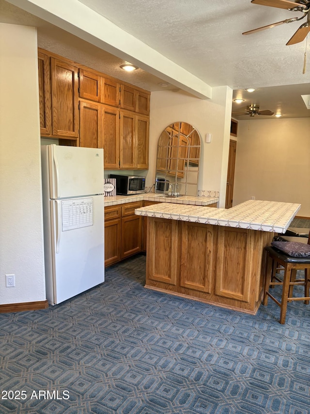 8426 N 15th Dr, Phoenix, AZ 85021 - kitchen with light countertops, stainless steel microwave, freestanding refrigerator, a textured ceiling, and ceiling fan