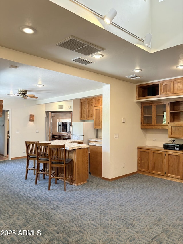 8426 N 15th Dr, Phoenix, AZ 85021 - kitchen with brown cabinets, carpet, a breakfast bar, visible vents, and freestanding refrigerator