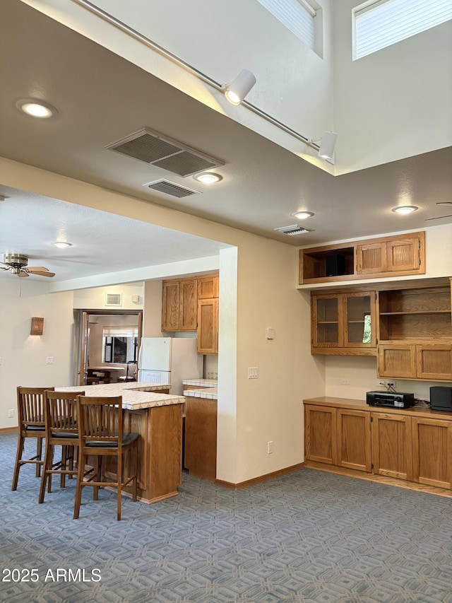 8426 N 15th Dr, Phoenix, AZ 85021 - kitchen featuring a kitchen breakfast bar, brown cabinets, light countertops, carpet flooring, and freestanding refrigerator