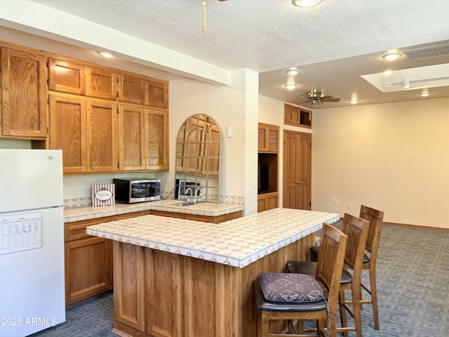 8426 N 15th Dr, Phoenix, AZ 85021 - kitchen with dark carpet, a ceiling fan, tile countertops, stainless steel microwave, and freestanding refrigerator