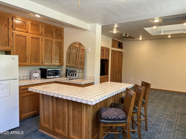 8426 N 15th Dr, Phoenix, AZ 85021 - kitchen with tile counters, dark colored carpet, a ceiling fan, stainless steel microwave, and freestanding refrigerator