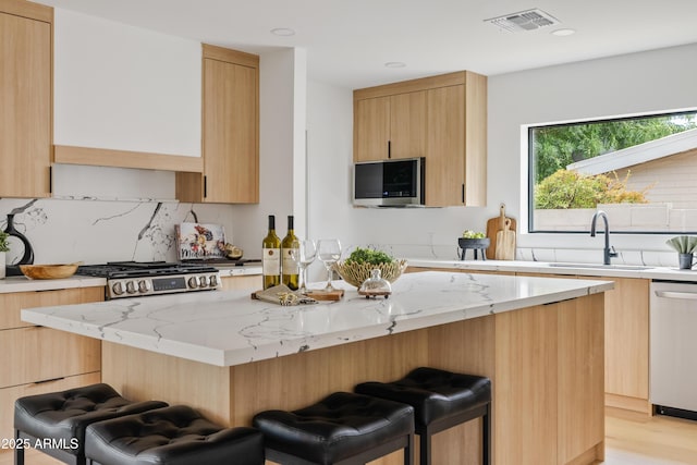 kitchen featuring light stone countertops, dishwasher, a center island, sink, and a breakfast bar