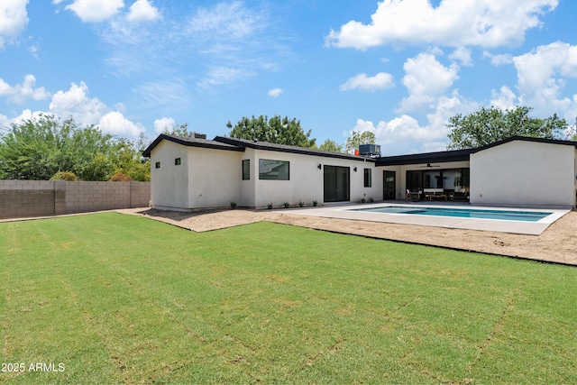 rear view of house featuring a fenced in pool, a patio area, ceiling fan, and a lawn