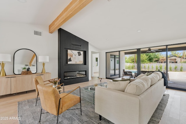 living room featuring vaulted ceiling with beams, ceiling fan, a fireplace, and light wood-type flooring