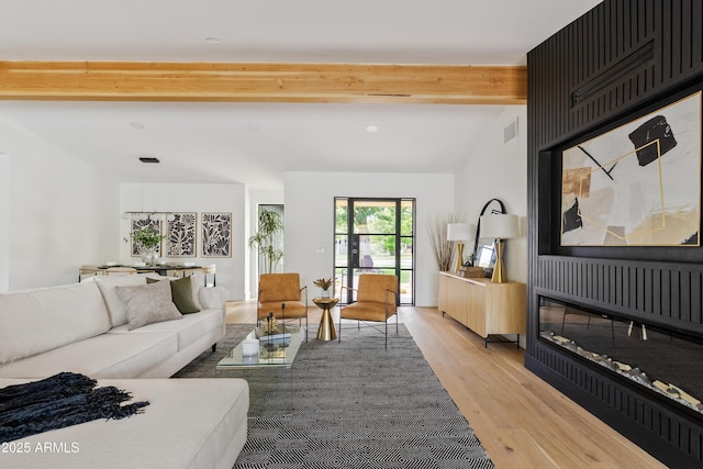 living room with vaulted ceiling with beams and light hardwood / wood-style floors