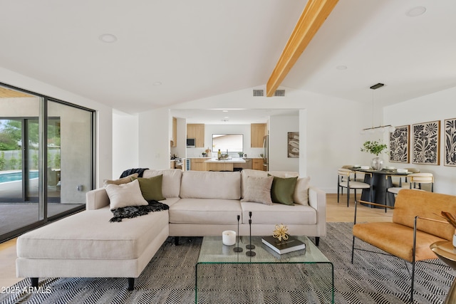 living room with vaulted ceiling with beams, a healthy amount of sunlight, and hardwood / wood-style flooring