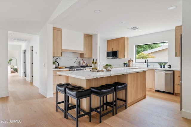 kitchen with dishwasher, a center island, a kitchen breakfast bar, and light stone counters