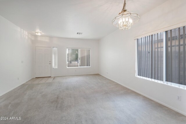 carpeted empty room with a notable chandelier