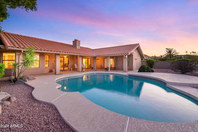 pool at dusk with a patio area