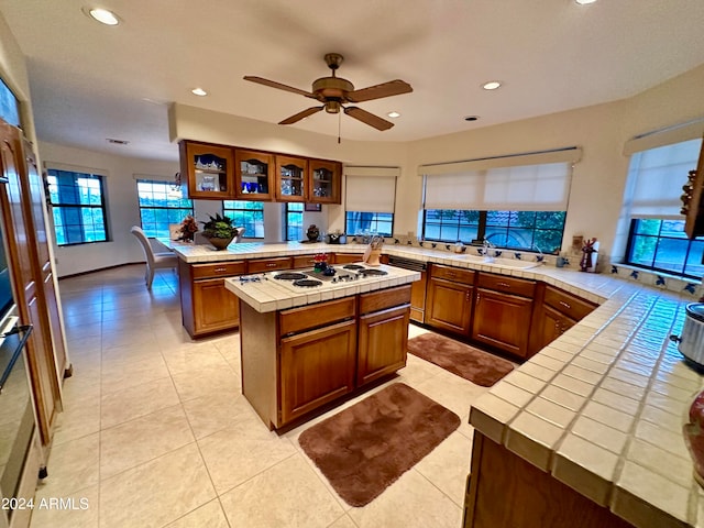 kitchen with a kitchen island, tile counters, ceiling fan, and light tile floors