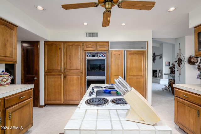 kitchen with paneled built in fridge, ceiling fan, and tile counters