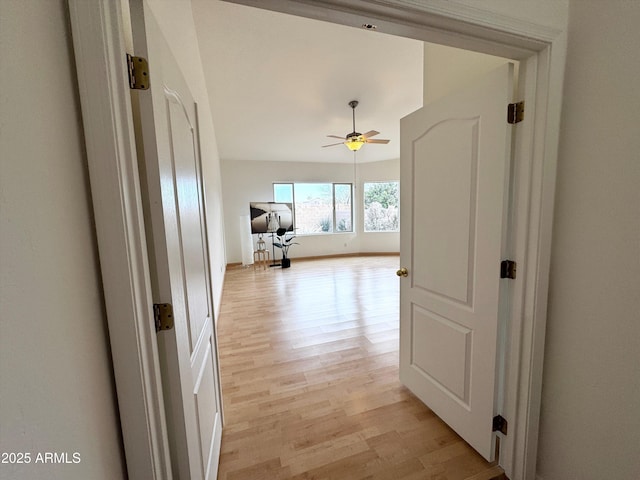 corridor featuring light wood-style flooring and baseboards