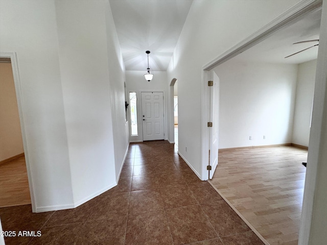 tiled foyer with arched walkways, a ceiling fan, and baseboards