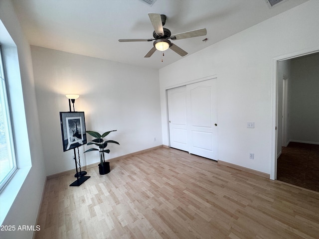 unfurnished bedroom featuring a closet, ceiling fan, baseboards, and wood finished floors