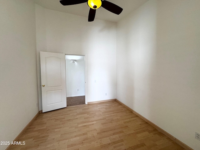 spare room featuring a high ceiling, baseboards, and light wood finished floors