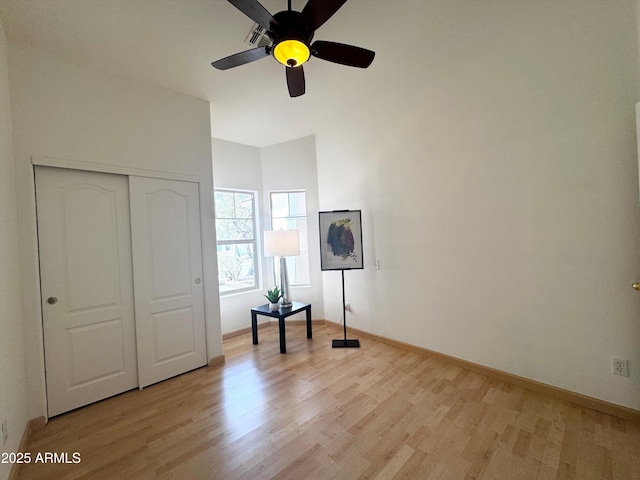 unfurnished bedroom with a ceiling fan, a closet, light wood-style flooring, and baseboards