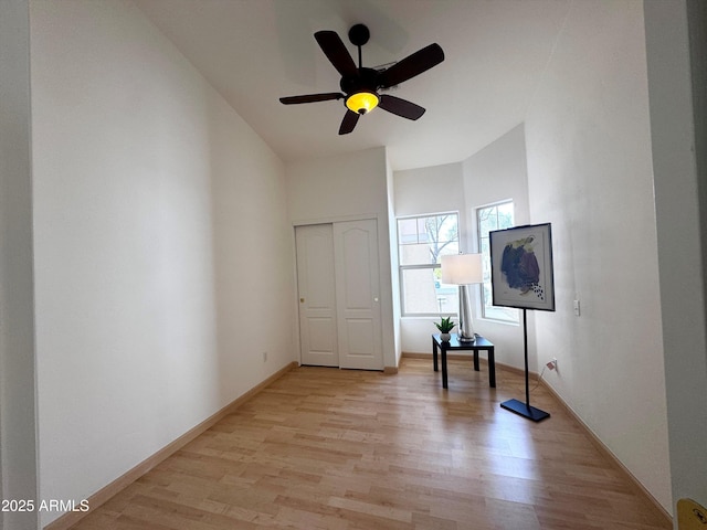 unfurnished bedroom featuring light wood-style floors, a closet, baseboards, and a ceiling fan