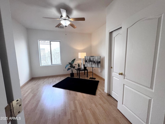 exercise room featuring ceiling fan, baseboards, and wood finished floors