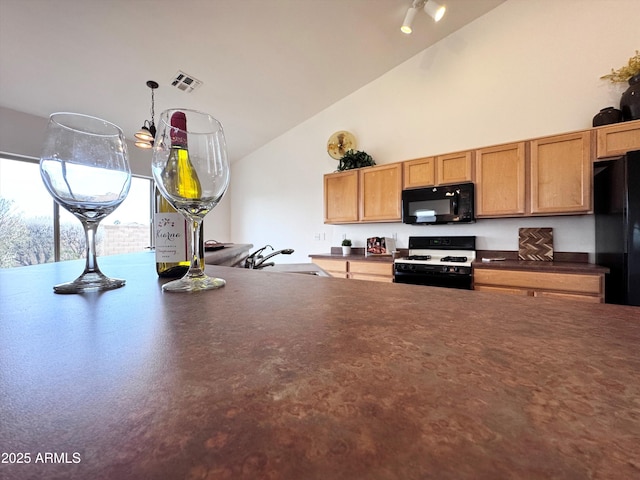 kitchen featuring high vaulted ceiling, a sink, visible vents, black appliances, and dark countertops