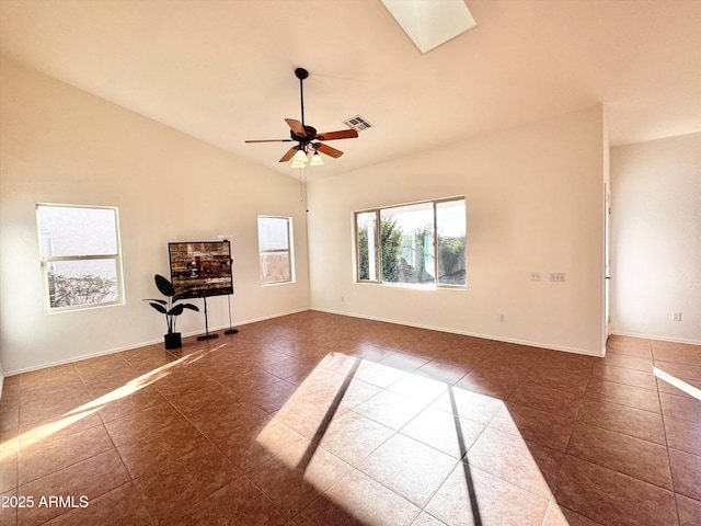 empty room with visible vents, lofted ceiling with skylight, a ceiling fan, tile patterned flooring, and baseboards