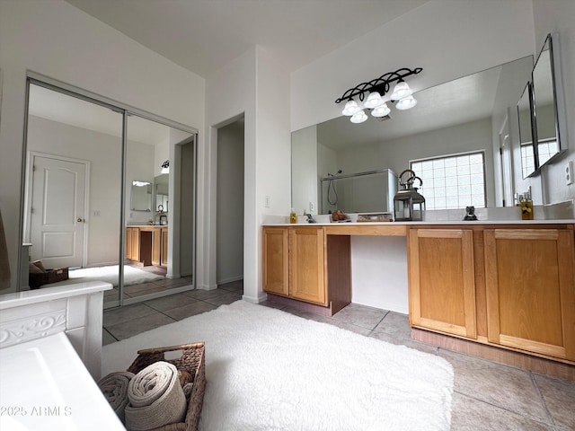 bathroom with tile patterned flooring, vanity, and walk in shower