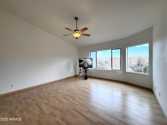 empty room featuring lofted ceiling, a ceiling fan, baseboards, and wood finished floors