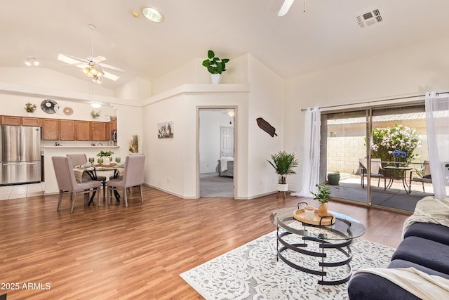 living area with ceiling fan, light wood-type flooring, high vaulted ceiling, and baseboards