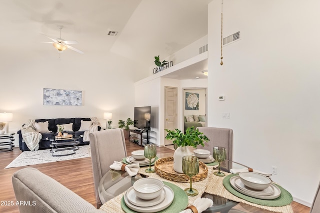 dining area with wood finished floors, high vaulted ceiling, and ceiling fan
