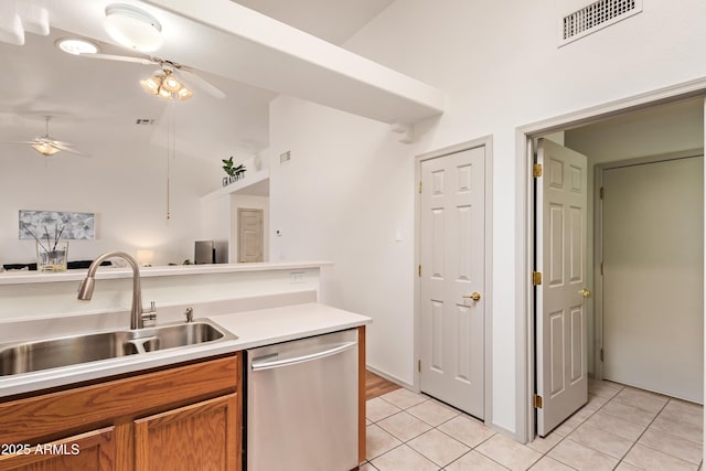 kitchen with stainless steel dishwasher, a ceiling fan, a sink, brown cabinets, and light tile patterned floors