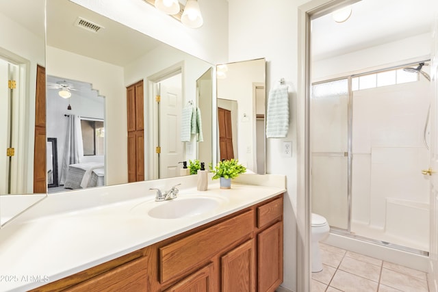 bathroom featuring a stall shower, tile patterned floors, toilet, vanity, and ceiling fan