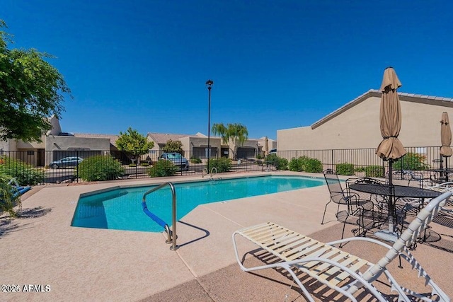 community pool featuring fence, a patio area, and a residential view