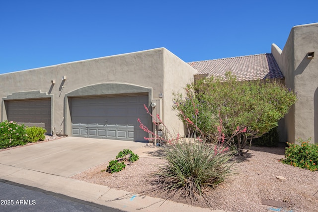 southwest-style home featuring concrete driveway, stucco siding, and a garage