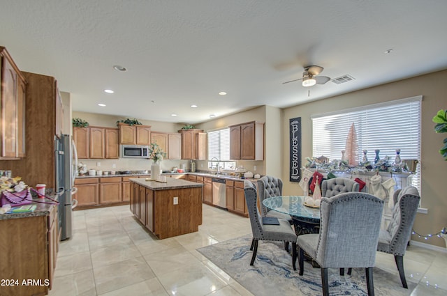 kitchen featuring stainless steel appliances, ceiling fan, sink, a center island, and light tile patterned flooring