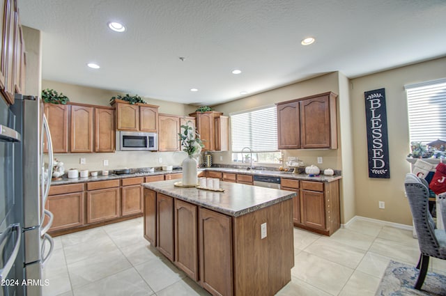 kitchen featuring a textured ceiling, a kitchen island, stainless steel appliances, and light tile patterned floors