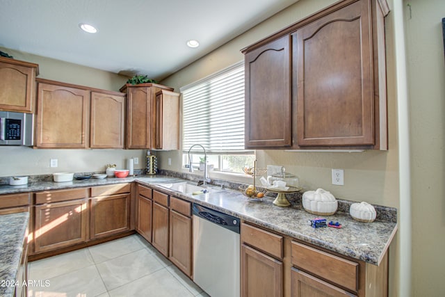 kitchen featuring dark stone counters, sink, light tile patterned floors, and stainless steel appliances